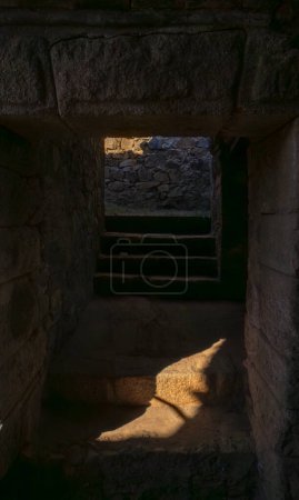 Téléchargez les photos : Escaliers rocheux à l'entrée d'un passage sombre de l'ancien théâtre romain de Mérida ou donjon d'un château médiéval faiblement éclairé en chiaroscuro par la lumière du soleil aube sur les escaliers et la sortie. - en image libre de droit
