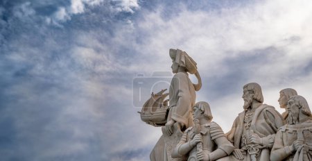 Foto de Perfil oriental con esculturas de piedra caliza y Henry el Navegante sosteniendo en su mano un barco del Monumento a los Descubrimientos de Lisboa con un espectacular cielo azul nublado. - Imagen libre de derechos