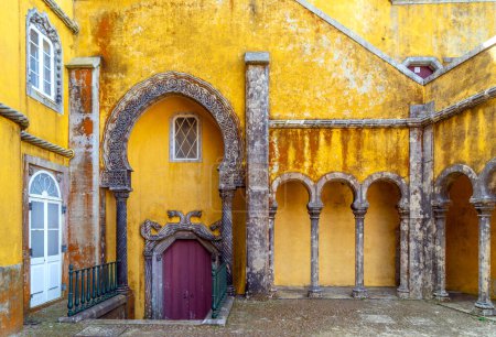 Innenraum des Bogenhofes mit wunderschön verzierten Bögen und Säulen im arabischen Stil und den gelb gestrichenen Wänden des Pena-Palastes in Sintra, Portugal.