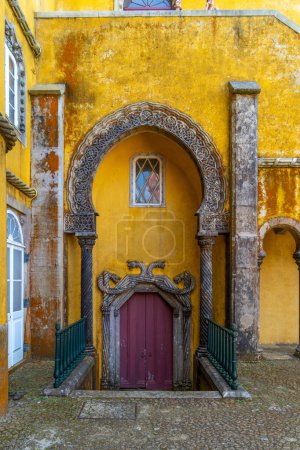 Geschnitzter Bogen mit Säulen im arabischen Stil und gelb bemalten Wänden des Pena-Palastes in Sintra, Portugal.
