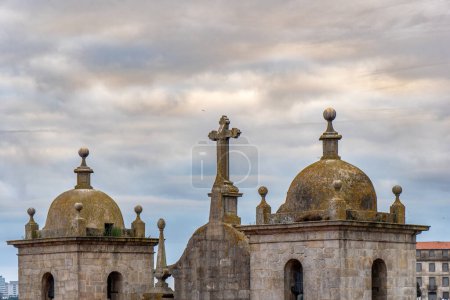 Luftaufnahme der Turmspitze der Kirche San Lorenzo de los Grillos mit ihren Kuppeln und Kreuzen in Porto, Portugal, unter einem subtil beleuchteten wolkenverhangenen Himmel.