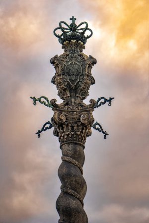 Détail de la colonne ornée sculptant le pilori ou pelourinho monument en pierre sur la place en face de la cathédrale Terreiro da Se, Porto, Portugal, sous un ciel nuageux et coloré coucher de soleil.