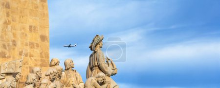 Denkmal der Entdeckungen aus Kalkstein: Heinrich der Navigator hält ein Schiff in der Hand, das auf das Meer hinausblickt, während ein Passagierflugzeug kopfüber vorbeifliegt, um in Lissabon zu landen.