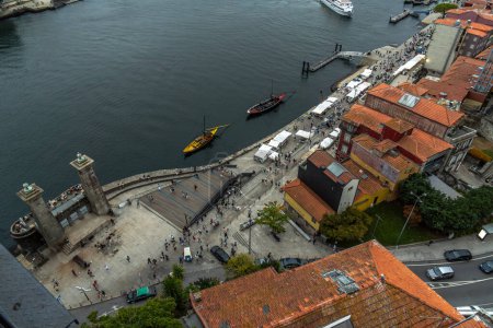 Widok z lotu ptaka na rzekę Douro i promenadę Porto z Rabelami, klasyczne łodzie dla szlaków turystycznych 6 mostów i restauracji oraz turystów spacerujących wzdłuż promenady rzeki.