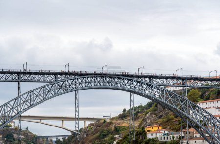 Frontalansicht vom Fluss der Stahlbrücke Don Luis I mit Menschen, die spazieren gehen, Fotos machen und posieren und drei weiteren Brücken im Hintergrund des Douro in Porto. Lissabon.
