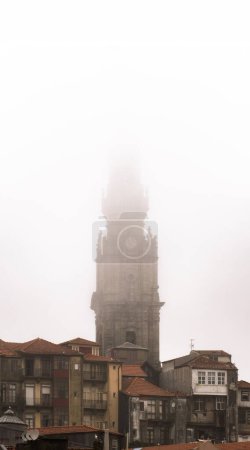 Die Kirche der Kleriker, barock aus dem 17. Jahrhundert, ragt zwischen den Häusern und Dächern des historischen Viertels von Porto hervor, verdeckt von Nebel und Regenwolken an einem romantischen und idyllischen grauen Tag..
