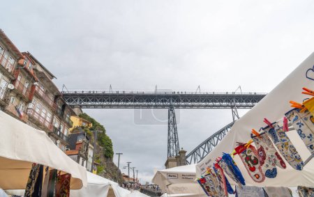 Foto de Mercado tradicional en Ribeira, en Vila de Gaia en Oporto, con el puente Dom Luis I al fondo con peatones caminando. - Imagen libre de derechos