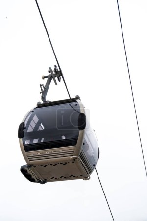 View from below of a Vila Nova de Gaia cable car gondola suspended on a steel cable under a cloudy white sky in Porto.