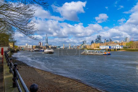 Photo for Panoramic view of the River Thames from Rotherhithe Promenade with views of Tower Bridge, London skyscrapers such as The Shard, and shipping traffic and tourist ferries sailing along the river. - Royalty Free Image
