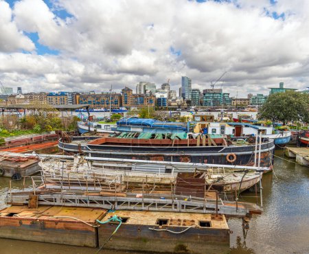 Sportboote und einige baufällige Boote liegen am Ufer der Themse an der Butler 's Wharf in London, England, Vereinigtes Königreich.