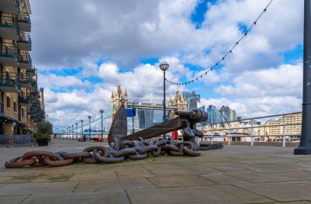 Grande ancre en fer avec sa chaîne appartenant à un navire agissant comme une sculpture sur la promenade de la Tamise avec le Tower Bridge et l'horizon de Londres en arrière-plan. Royaume-Uni.