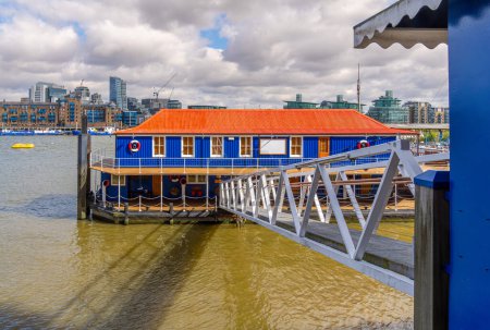 The Harpy houseboat illuminated by morning sunlight on the south bank of the River Thames, Bermondsey, London, England.