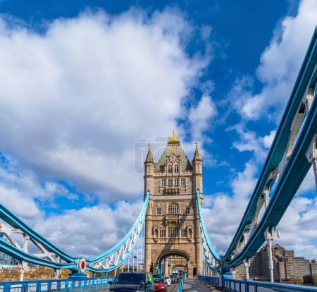 View of traffic jam on Tower Bridge in London, under a sunny sky with white clouds.