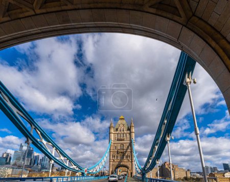 Blick aus dem Inneren eines der Türme der Tower Bridge in London, mit Blick auf die Bauwerke in der Perspektive und Touristen und Autos, die auf der Straße unterwegs sind, mit der Londoner Skyline im Hintergrund.