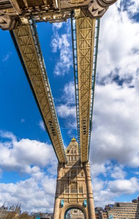 Blick von unten auf die Tower Bridge, mit Blick auf die Korridore und die oberen Plattformen der Laufstege mit Glasplatten am Boden unter einem sonnigen Himmel mit weißen Wolken in London.