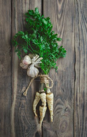 Parsley and garlic on wooden background. Fresh organic parsley herb leaves. Parsley and garlic.The concept of natural and healthy nutrition. From the garden. Cooking. Vegan food. Useful product. Poster 647378018