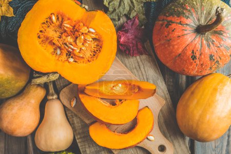 Pumpkins on the table. Autumnal Background. Halloween party. Thanksgiving day. Halloween decor with various pumpkins, autumn vegetables and flowers. Harvest and decoration.Thanksgiving day concept.