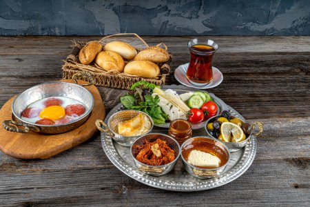 Photo for Healthy traditional Turkish breakfast, scrambled eggs with sausage ,cheeses ,olives ,tomatoes ,cucumbers.etc. served on a tray with tea - Royalty Free Image