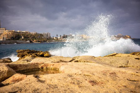Photo for A lot of spray from the waves of the ocean against the backdrop of the buildings of the city of Valletta. Coast of the island of Malta in winter. High quality photo - Royalty Free Image