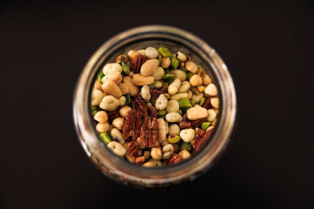 Photo for Various types of nuts and seeds in a glass jar close-up, top view. A light snack. High quality photo - Royalty Free Image