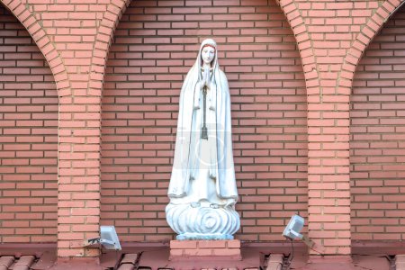 Statue of the image of Our Lady of Ftima, mother of God in the Catholic religion, Our Lady of the Rosary of Fatima, Virgin Mary with the background of a brick wall in Brazil