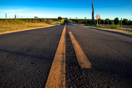 Carretera de asfalto rural con señales de velocidad y líneas y marcadores pintados en el suelo, en Brasil