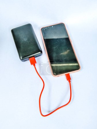 Photo for Cellphone being charged using a power bank with isolated white background - Royalty Free Image