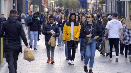 Foto de Crowd of people walking through a busy pedestrian zone - Grafton Street Dublin in slow motion - CITY OF DUBLIN, IRELAND - APRIL 20, 2022 - Imagen libre de derechos