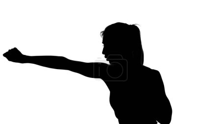 Foto de Sobre un fondo blanco, una sombra, un contorno negro de una figura femenina haciendo movimientos de boxeo, una lucha con una sombra, kickboxing, imitaciones de golpes, técnicas de combate,. Foto de alta calidad - Imagen libre de derechos