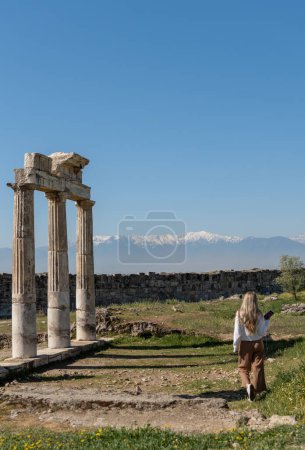 Photo for Rear view of woman at Roman ruins with snow-capped mountain peaks in the background in Turkey - Royalty Free Image