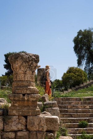 Téléchargez les photos : Femme touristique blonde méconnaissable avec chapeau dans les ruines Jerash antiques en Jordanie - en image libre de droit