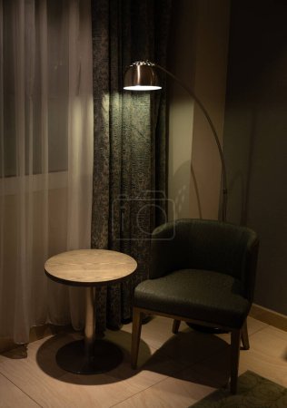 Vertical photo of the interior space of a vintage living room with lamp, chair and table