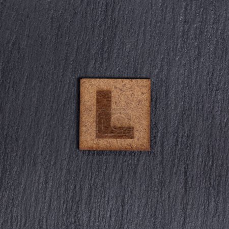 Photo for Capital Letter In Square Wooden Tiles - Letter L, On Black Stone Background. - Royalty Free Image