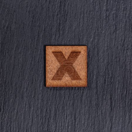 Photo for Capital Letter In Square Wooden Tiles - Letter X, On Black Stone Background. - Royalty Free Image