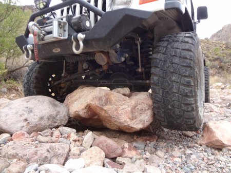 Téléchargez les photos : White Jeep Wrangler with Big Tires Stuck on Rock. High quality photo - en image libre de droit