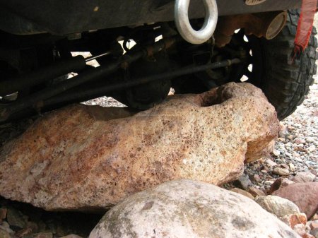 Téléchargez les photos : Big Tires on Capable SUV Stuck on Boulder. High quality photo - en image libre de droit