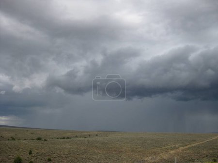 Téléchargez les photos : Dark Storm Clouds by Highway Vering Rain Over Rolling Hills. Photo de haute qualité - en image libre de droit