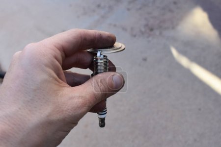 Hand Gapping a Spark Plug with Tool in the Driveway . High quality photo