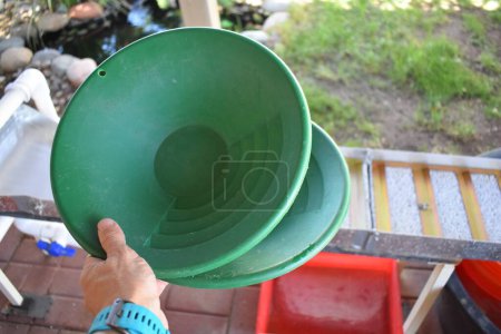 Photo for Hand Holding Two Empty Green Plastic Gold Pans by Sluice, Gold Mining Equipment. High quality photo - Royalty Free Image