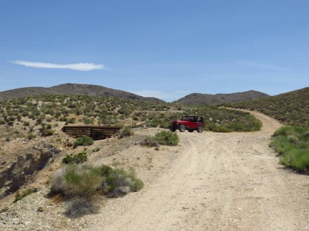 Téléchargez les photos : Véhicule rouge stationné sur le chemin Dirt près de l'entrée de la mine dans le parc national Death Valley. Photo de haute qualité - en image libre de droit