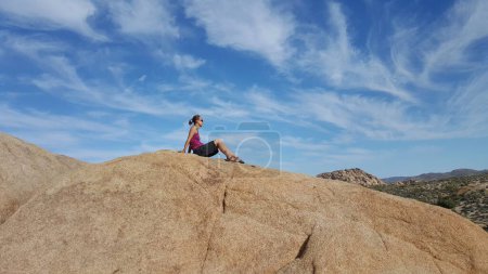 Fit Woman assis sur le dessus de Boulder dans Joshua Tree National Park, Californie. Photo de haute qualité