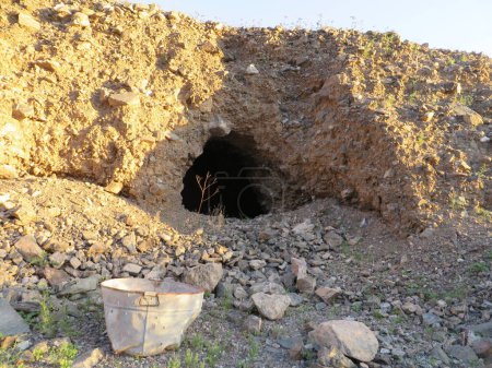 Sitio de minas abandonadas con cubo oxidado en el desierto de Arizona. Este agujero en el aluvión es probablemente un refugio. Se encuentra en una antigua mina en Arizona. Foto de alta calidad