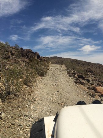 Offroad Adventure Driving White Vehicle auf einer Schotterstraße in der kalifornischen Wüste. Hochwertiges Foto