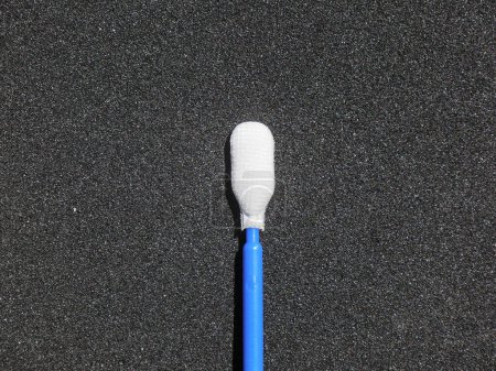 Foto de Un hisopo oral de un laboratorio de análisis médico sobre fondo negro. El palo de retención es azul. - Imagen libre de derechos
