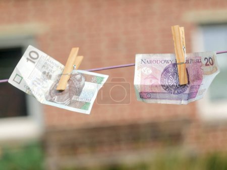 Photo for Zloty (polish currency) banknotes hanging from a clothesline, with clothespins, on blurry background. For tainted money concept or money laundering. - Royalty Free Image
