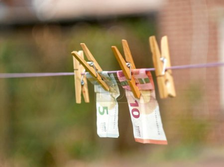 Photo for Euro Banknotes hanging from a clothesline, with clothespins, on blurry background. For tainted money concept or money laundering. - Royalty Free Image