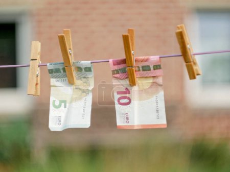 Photo for Euro Banknotes hanging from a clothesline, with clothespins, on blurry background. For tainted money concept or money laundering. - Royalty Free Image