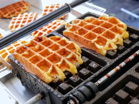 Photo for Two Liege waffles baking on their mold. - Royalty Free Image