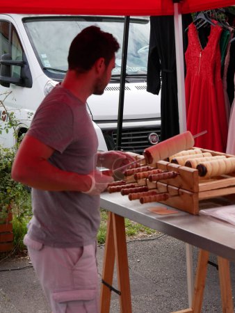Téléchargez les photos : Arleux, France - 09 02 2023 : Préparation d'un kurtoskalacs (gâteau à la broche hongrois de Transylvanie) dans un étal de marché. - en image libre de droit