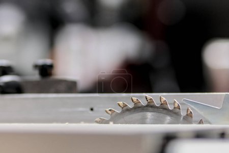 Photo for Table saw blade, protruding slightly from its table, in front of a cutting guide. - Royalty Free Image